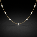 Gold necklace with white beads on a black background