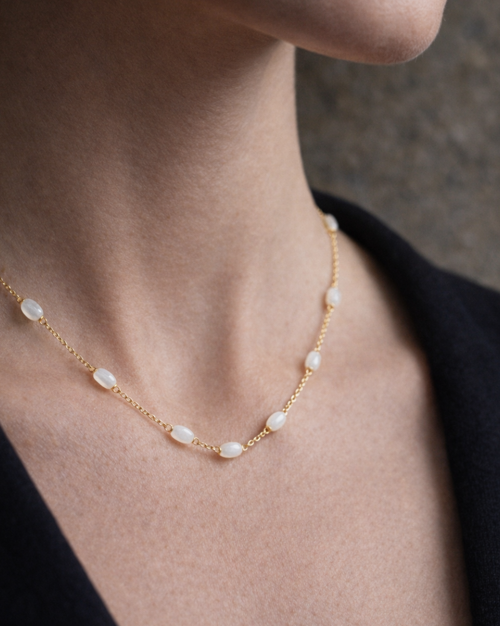 Pearl necklace on a person's neck with a neutral background